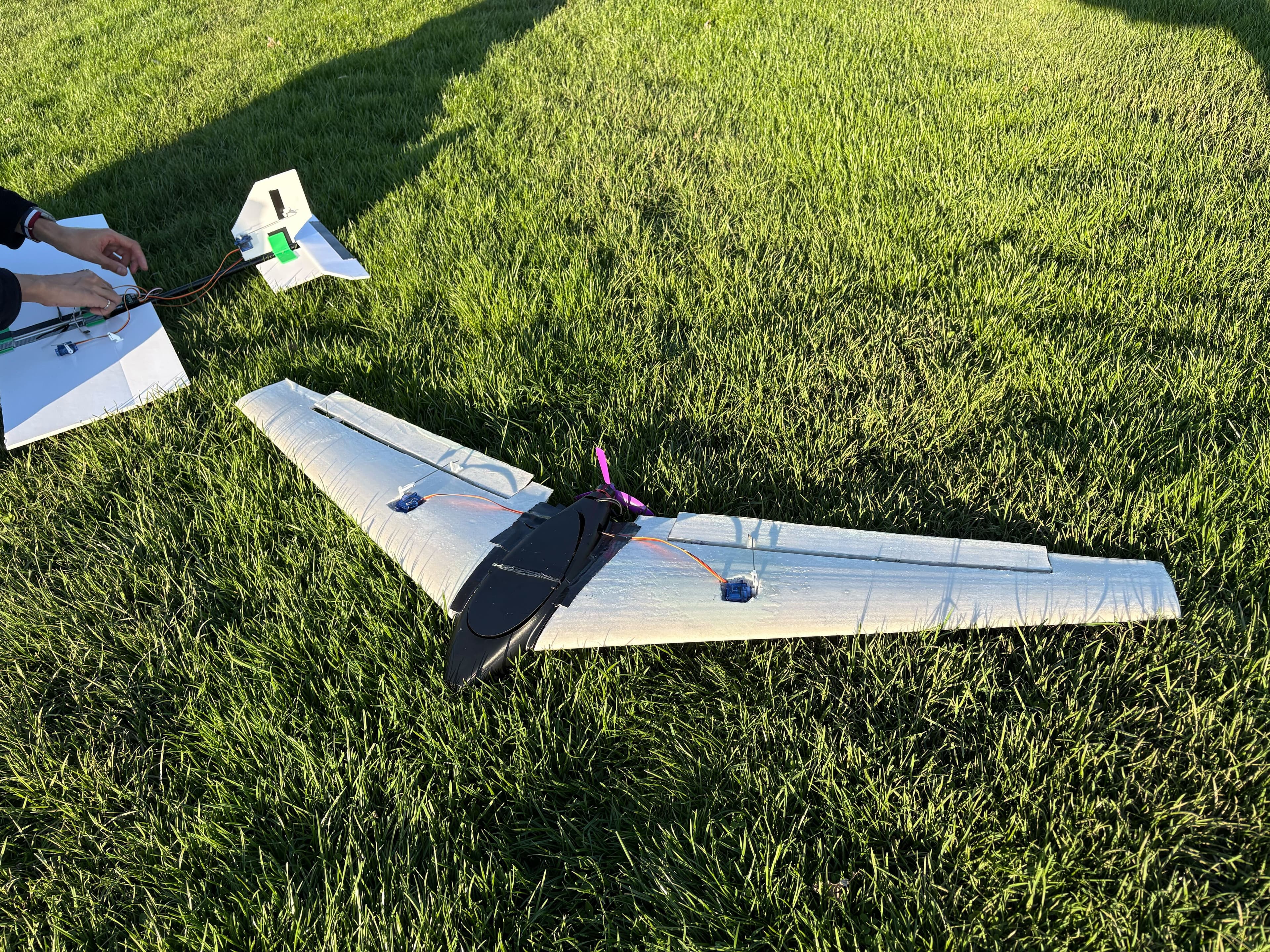 Foam airframe and electronics laid out on grass during a field test